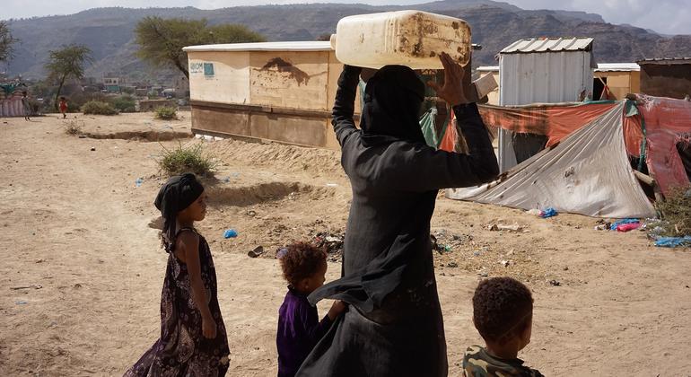 也门塔伊兹，一位母亲带着孩子将水运到临时避难所。